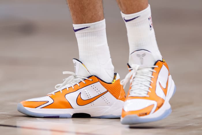 View of Devin Booker's orange and white Nike shoes.